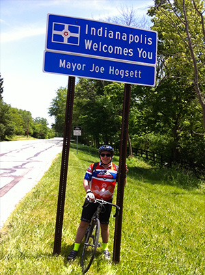 骑自行车的人Mike Blacconiere站在印第安纳波利斯欢迎标志，途中乘坐前往普雷斯坦，步行到结束胰腺癌