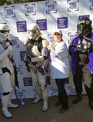 胰腺癌幸存者站在筹款者步行中穿着白色的冲锋衣盔甲