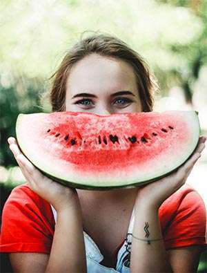 年轻女子准备吃西瓜，因为水果是健康饮食的一部分。