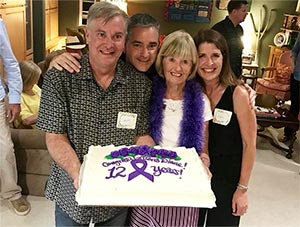 朋友和家人与庆祝12年胰腺癌幸存者的蛋糕合影