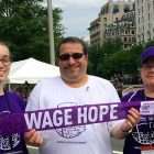 胰腺癌幸存者与他的妻子和女儿在PurpleStride举着“工资希望”的横幅