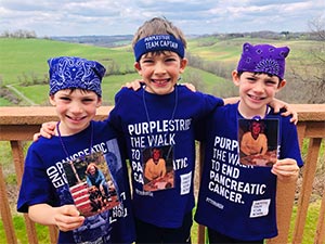胰腺癌的三个男孩穿着紫色潘山T恤与他们的格莱美照片