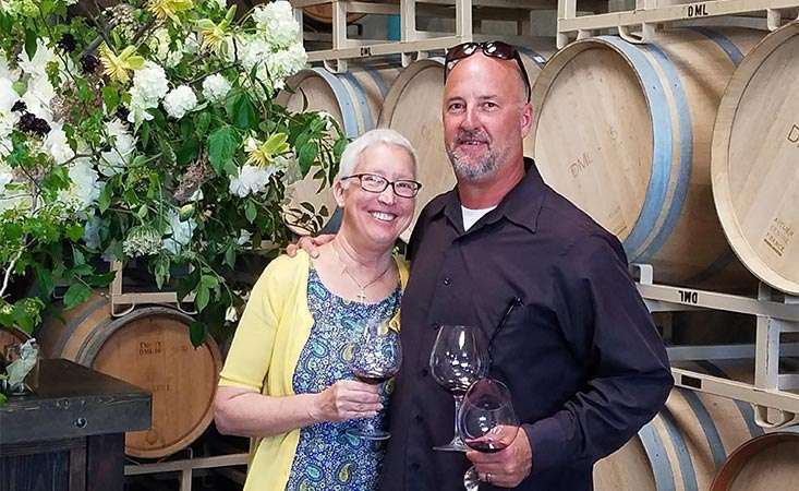 胰腺癌患者和她的丈夫站在他们公司的几桶酒前。