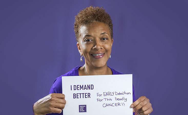 一名志愿者举着一个牌子，上面写着她为什么要求胰腺癌患者得到更好的治疗。