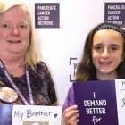 妈妈和女儿拿着激发她们胰腺癌志愿服务的家庭成员的照片