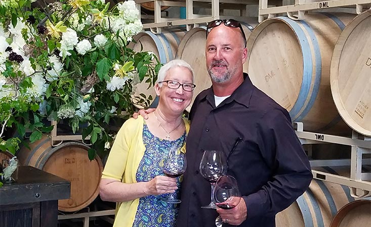 一位胰腺癌患者和她的丈夫站在他们葡萄酒公司的几桶酒前。