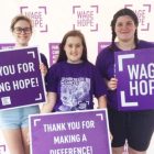 一个高中生和她的两个朋友在结束胰腺癌的步行中手持希望的信号